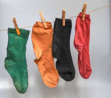 Eine grüne, eine gelbe , eine schwarze und eine rote Socke hängen an einer Wäscheleine. Die Socken tragen die Farben der massgeblichen politischen Parteien, die sich im Parteienstreit messen und um Profilierung kämpfen. Vor zwölf Monaten ist die schwarz-rote Regierung vereidigt worden. Foto:Winfried Rothermel