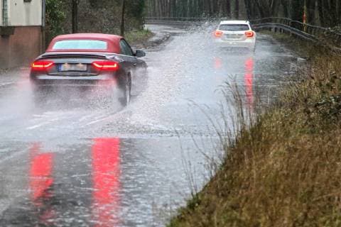 Gefährliche Straßenverhältnisse bei Starkregen. Das Wasser von einer nach Starkregen überfluteten Straße wird von den Autos in die Luft gerissen und sorgt bei vielen Fahrern für Schrecksekunden. Essen Nordrhein-Westfalen Germany - Deutschland Überruhr