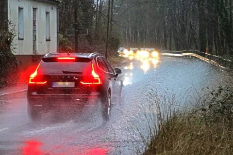 Gefährliche Straßenverhältnisse bei Starkregen. Das Wasser von einer nach Starkregen überfluteten Straße wird von den Autos in die Luft gerissen und sorgt bei vielen Fahrern für Schrecksekunden. Essen Nordrhein-Westfalen Germany - Deutschland Überruhr