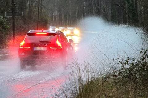 Gefährliche Straßenverhältnisse bei Starkregen. Das Wasser von einer nach Starkregen überfluteten Straße wird von den Autos in die Luft gerissen und sorgt bei vielen Fahrern für Schrecksekunden. Essen Nordrhein-Westfalen Germany - Deutschland Überruhr