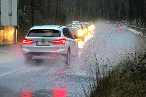 Gefährliche Straßenverhältnisse bei Starkregen. Das Wasser von einer nach Starkregen überfluteten Straße wird von den Autos in die Luft gerissen und sorgt bei vielen Fahrern für Schrecksekunden. Essen Nordrhein-Westfalen Germany - Deutschland Überruhr
