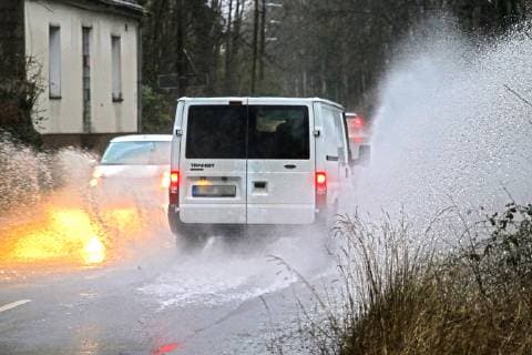 Gefährliche Straßenverhältnisse bei Starkregen. Das Wasser von einer nach Starkregen überfluteten Straße wird von den Autos in die Luft gerissen und sorgt bei vielen Fahrern für Schrecksekunden. Essen Nordrhein-Westfalen Germany - Deutschland Überruhr