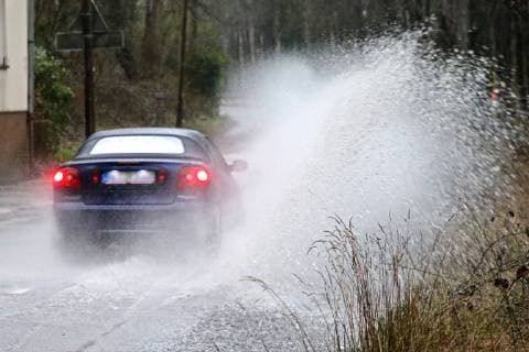 Gefährliche Straßenverhältnisse bei Starkregen. Das Wasser von einer nach Starkregen überfluteten Straße wird von den Autos in die Luft gerissen und sorgt bei vielen Fahrern für Schrecksekunden. Essen Nordrhein-Westfalen Germany - Deutschland Überruhr