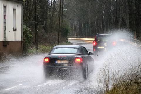 Gefährliche Straßenverhältnisse bei Starkregen. Das Wasser von einer nach Starkregen überfluteten Straße wird von den Autos in die Luft gerissen und sorgt bei vielen Fahrern für Schrecksekunden. Essen Nordrhein-Westfalen Germany - Deutschland Überruhr
