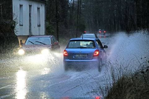 Gefährliche Straßenverhältnisse bei Starkregen. Das Wasser von einer nach Starkregen überfluteten Straße wird von den Autos in die Luft gerissen und sorgt bei vielen Fahrern für Schrecksekunden. Essen Nordrhein-Westfalen Germany - Deutschland Überruhr