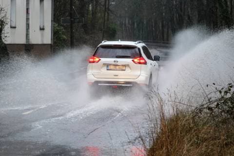 Gefährliche Straßenverhältnisse bei Starkregen. Das Wasser von einer nach Starkregen überfluteten Straße wird von den Autos in die Luft gerissen und sorgt bei vielen Fahrern für Schrecksekunden. Essen Nordrhein-Westfalen Germany - Deutschland Überruhr