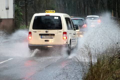 Gefährliche Straßenverhältnisse bei Starkregen. Das Wasser von einer nach Starkregen überfluteten Straße wird von den Autos in die Luft gerissen und sorgt bei vielen Fahrern für Schrecksekunden. Essen Nordrhein-Westfalen Germany - Deutschland Überruhr