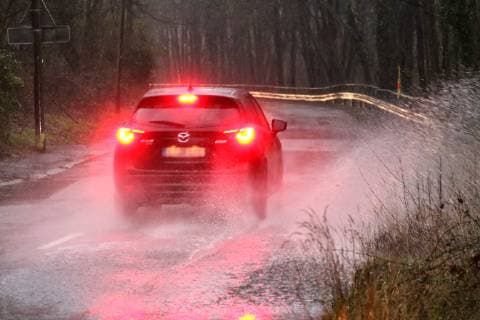 Gefährliche Straßenverhältnisse bei Starkregen. Das Wasser von einer nach Starkregen überfluteten Straße wird von den Autos in die Luft gerissen und sorgt bei vielen Fahrern für Schrecksekunden. Essen Nordrhein-Westfalen Germany - Deutschland Überruhr