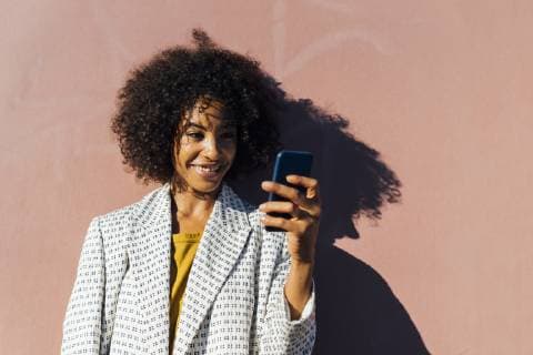 IMAGO Creative: Clickbait, Modetrends Beautiful woman standing in front of wall, taking pictures with her smartphone model released Symbolfoto  BOYF01312