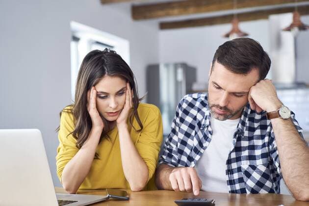 Worried couple sitting at dining table, using laptop, checking finances model released Symbolfoto property released  BSZF00875