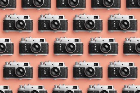 Photo cameras organized in a row over coral color background  DRBF00128
