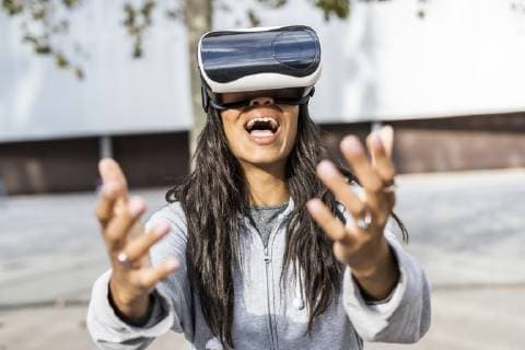 Young woman using VR goggles in the city, reaching out model released Symbolfoto  GIOF05389