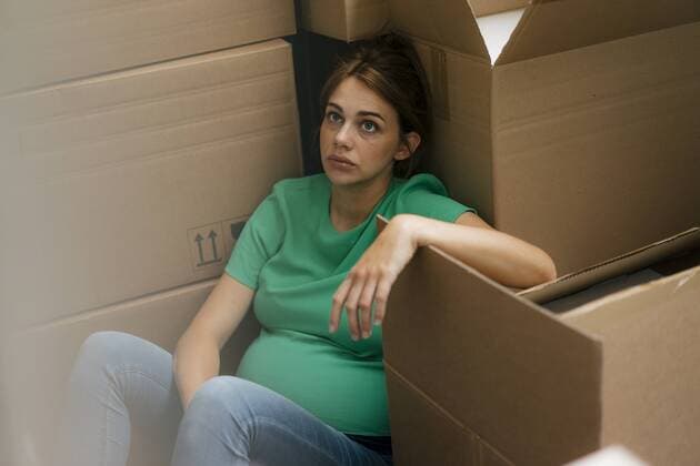 Exhausted pregnant woman sitting on floor surrounded by cardboard boxes model released Symbolfoto property released  KNSF05444