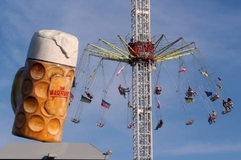 News Themen der Woche KW16 News Bilder des Tages Cannstatter Wasen Frühlingsfest am Ostersonntag in Stuttgart Bad Cannstatt, Baden Württemberg, Deutschland: überdimensioniertes Glas Bier Wasenwirt auf dem Dach eines Festzelt es vor einem sich drehenden Fahrgeschäft s bei strahlend blauem Himmel.