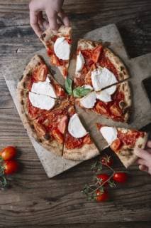 Eating a pizza with mozzarella, hand taking pizza slice model released Symbolfoto  ALBF00815