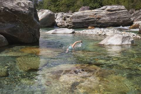 Switzerland, Ticino, Verzasca Valley, woman swimming in refreshing Verszasca river model released Symbolfoto  GWF05965