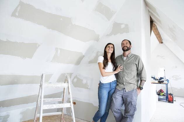Confident couple standing in attic to be renovated looking up model released Symbolfoto property released  MFRF01200