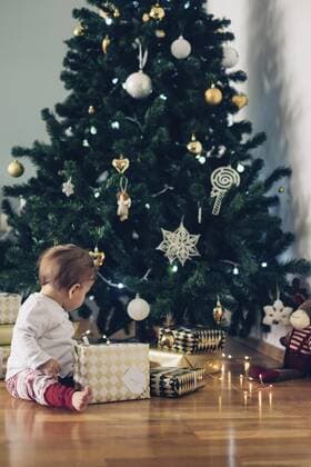 Baby girl sitting on the floor playing with Christmas gifts model released Symbolfoto  MOMF00628