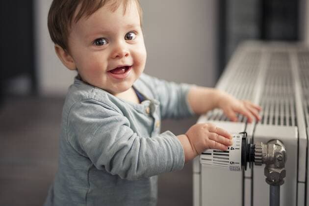 Portrait of smiling baby boy playing with thermostat of heater model released Symbolfoto property released  SEBF00022