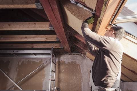 Roof insulation, worker filling pitched roof with wood fibre insulation model released Symbolfoto property released  SEBF00036