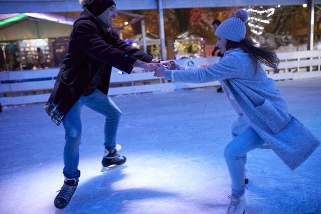 IMAGO Creative, Jahreszeit Winter, Eislaufen Happy young couple ice skating on an ice rink at night model released Symbolfoto property released  ZEDF01891