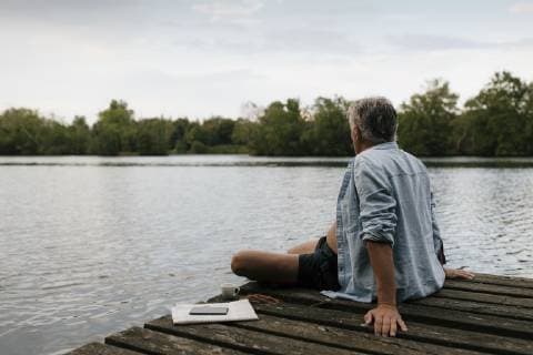 Senior man sitting on jetty at a lake model released Symbolfoto  GUSF01839