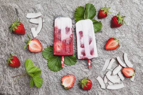 Homemade strawberry coconut ice lollies with fresh strawberries and coconut slices on granite  GWF05711