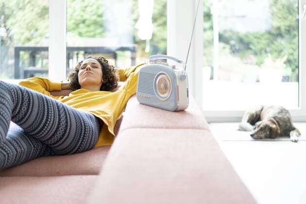 Woman lying on couch listening to music with portable radio at home model released Symbolfoto property released  JOSF02698