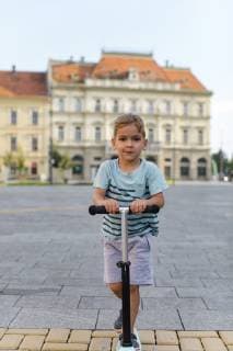 IMAGO Creative: Stadt-Dichotomien Portrait of boy riding a scooter in the city model released Symbolfoto  MOMF00618