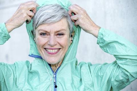Portrait of smiling sporty mature woman putting on hood of her jacket model released Symbolfoto  VWF00035