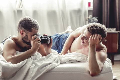 Gay man taking picture of his partner with old-fashioned camera in bed model released Symbolfoto  VWF00053