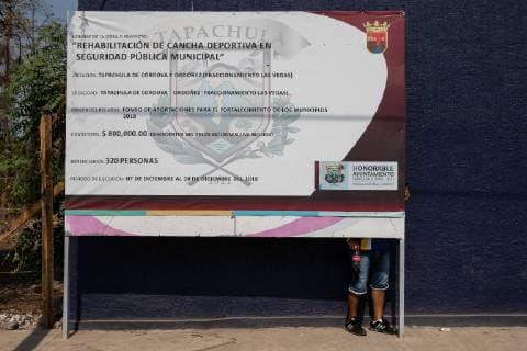 A man hides from the sun behind a Municipal poster in Tapachula, Mexico on May 6, 2019. Some migrants enter Mexico at this southern border town and then travel freely north to the United States border.  TP20190506101 ARIANAxDREHSLER