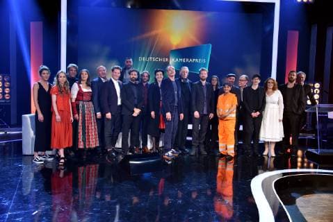 Gruppenbild mit allen Preisträgern und Laudatoren 2019 auf der Bühne bei der Preisverleihung des 29. Deutschen Kamerapreises. Hier werden Kameraleute und Editoren für ihre herausragende Leistung ausgezeichnet.