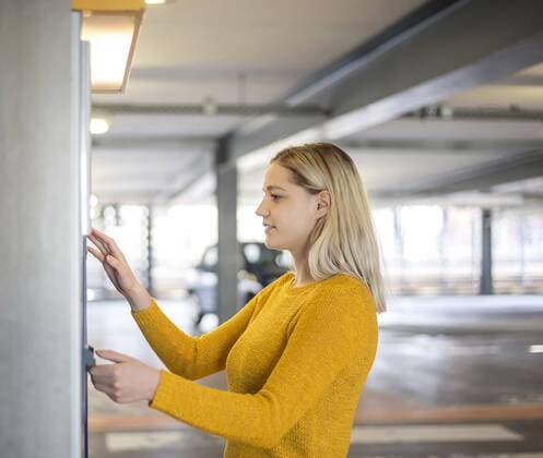 junge Frau am Parkscheinautomat