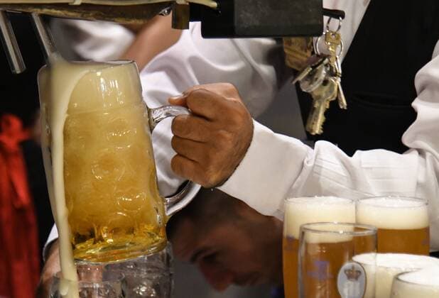 Hofbräuhaus München: frisches Hofbräu-Bier läuft aus dem Zapfhahn in einen Masskrug,