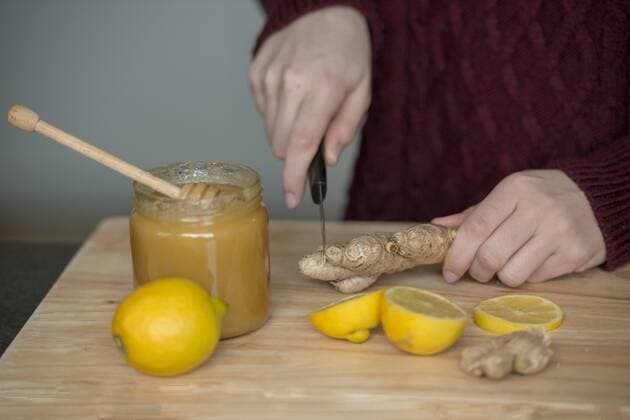 Hands of young woman cutting ginger root on wooden board model released Symbolfoto  LBF02421