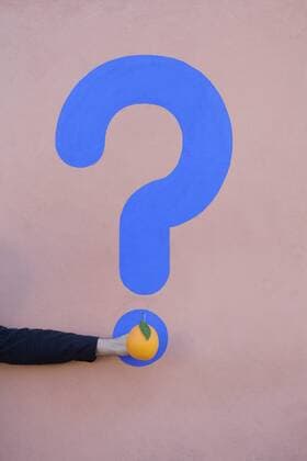 Man s hand holding an orange at a wall with question mark model released Symbolfoto  PSTF00370