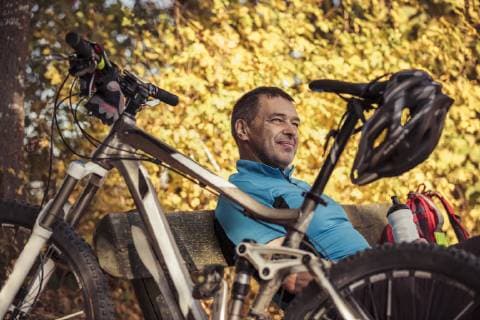 IMAGO Creative: Fit durch den Herbst Man with mountainbike having a break sitting on a bench model released Symbolfoto  SEBF00061