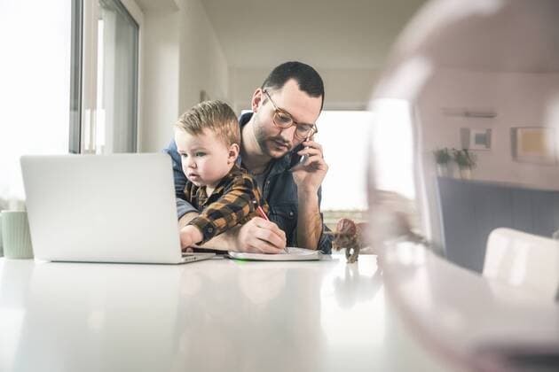 Busy father working at table in home office with son sitting on his lap model released Symbolfoto property released  UUF16867