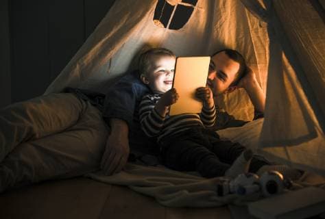 IMAGO Creative, Weihnachten, Tradition: Weihnachtsfilme sehen Father and son sharing a tablet in a dark tent at home model released Symbolfoto property released  UUF16879