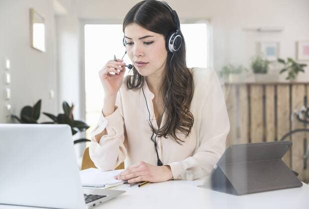 Young woman sitting at table at home wearing a headset model released Symbolfoto property released  UUF16974