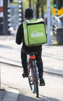 Amsterdam, Niederlande, Kuriere des Lebensmittel Online Lieferdienst Uber Eats, Fahrradlieferant und Lieferkurier zu Fuss,