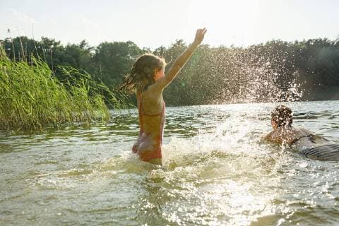 Playful girl splashing and woman swimming in sunny summer lake Germany Brandenburg  Copyright: SvenxHagolani fStopImages1813087