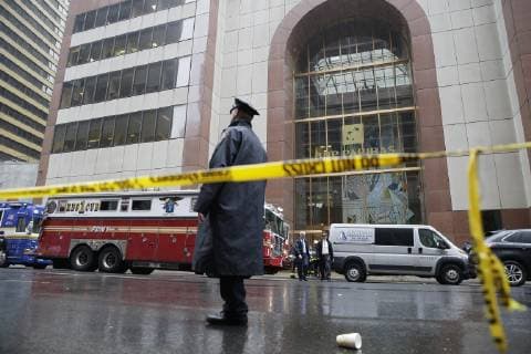 NYPD police officers stand outside the site of a helicopter crash on a rooftop in Midtown Monday afternoon on June 10, 2019 in New York City. A helicopter made a force or emergency landing on top of the building at 787 Seventh Avenue. The pilot of the helicopter was killed.  NYP20190610107 JOHNxANGELILLO
