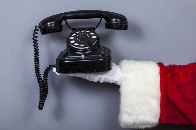 Weihnachstmann hält schwarzes altes Telefon
