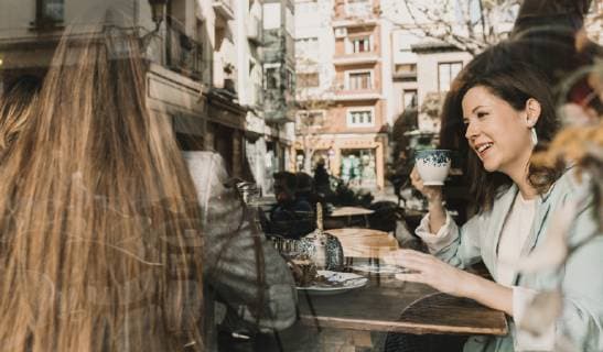 Two young women behind windowpane in a cafe model released Symbolfoto  AHSF00114