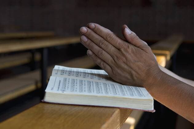 Praying hands on hymnbook on pew model released Symbolfoto  ASF06429
