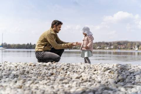 IMAGO Creative: Vaterschaft Germany, Bavaria, Herrsching, father and daughter on pebble beach at lakeshore model released Symbolfoto  DIGF06741