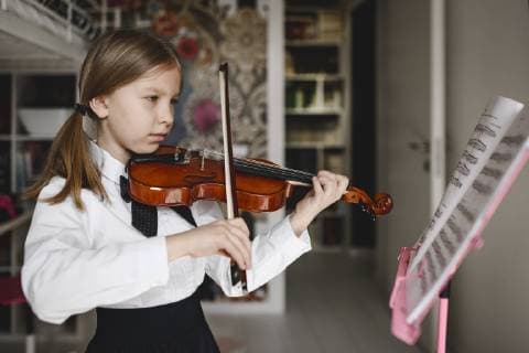 IMAGO Creative: Lokalhelden - Kunst und Kultur Girl playing violin looking at music stand at home model released Symbolfoto property released  EYAF00215