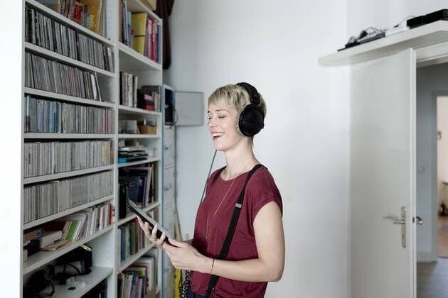 Happy woman listening to music with headphones at home model released Symbolfoto property released  FLLF00145